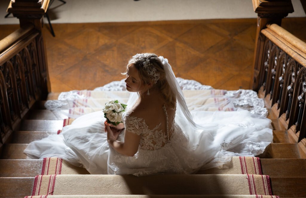 Picture of bridal model sat on a staircase at Carlton Towers wearing a custom made head piece and earrings designed and crafted by Fiona of Fifi and the Peacock