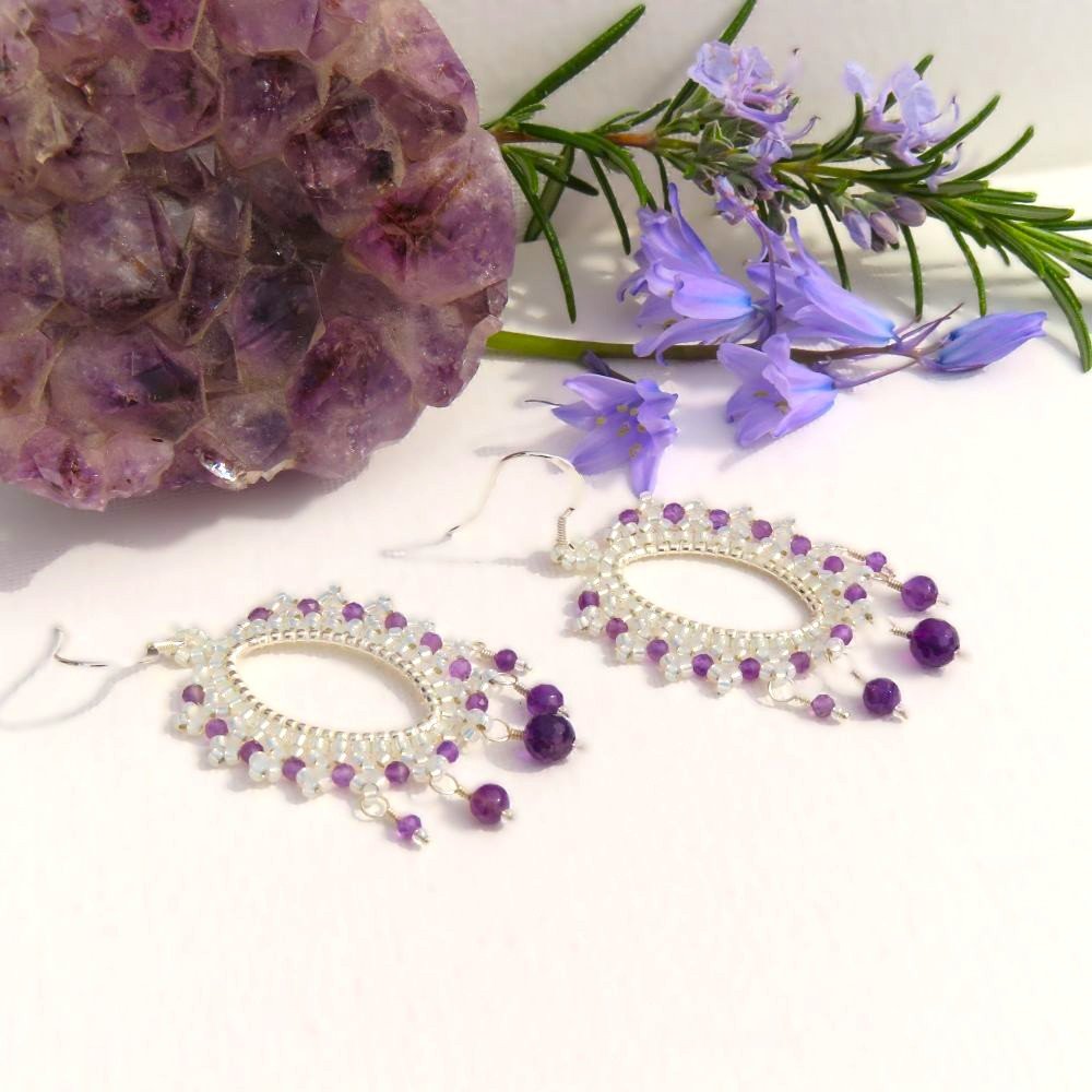 A sterling silver patterned elipse shaped frame has been embellished with Miyuki seed beads and micro faceted Amethysts.  Three different sizes of Amethyst drop from the base of each earring and they are on sterling silver ear wires.  Designed and crafted by Fiona of Fifi and the Peacock