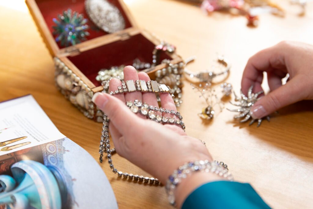 A picture of Fiona looking at her collection of jewellery inherited from her Grandma, Nana and Mum.  Shows Fionas love of jewellery from an early age.
