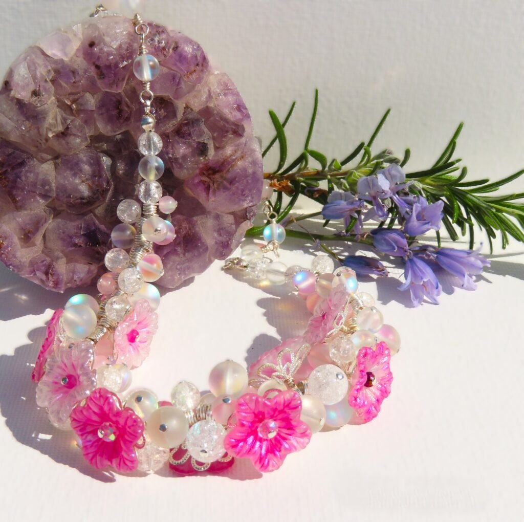 Gem heavy cluster necklace interspersed with hand painted lucite flowers with faceted glass crystal centres.  Clear crackled quartz, Rose Quartz and pink and white Mermaid crystals.  Designed and crafted by Fiona of Fifi and the Peacock