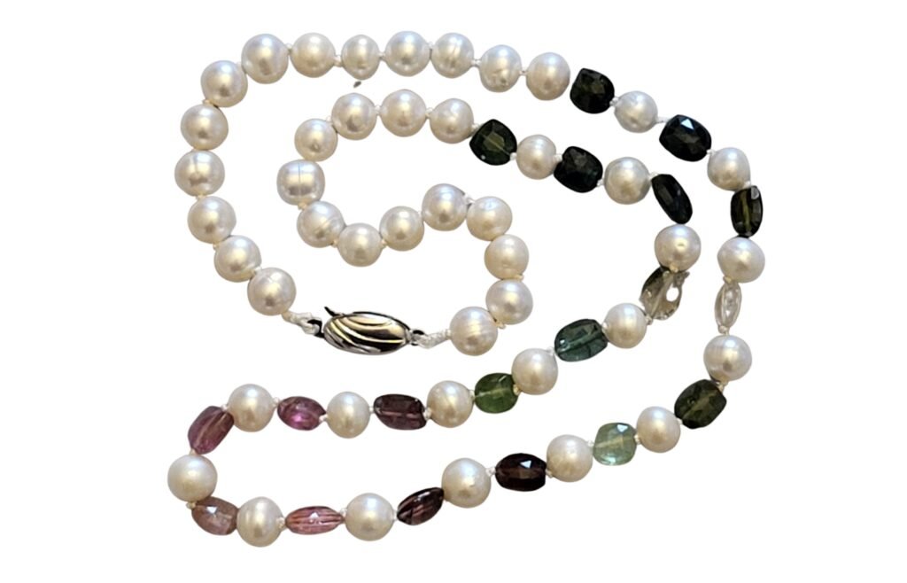 A totally unique necklace designed and crafted by Fiona of Fifi and the Peacock using the traditional pearl knotting technique.  This necklace features faceted multi coloured Tourmaline shield shaped beads and Cultured Freshwater Pearls.  This stunning heirloom piece is part of the A Thread Through Time Collection